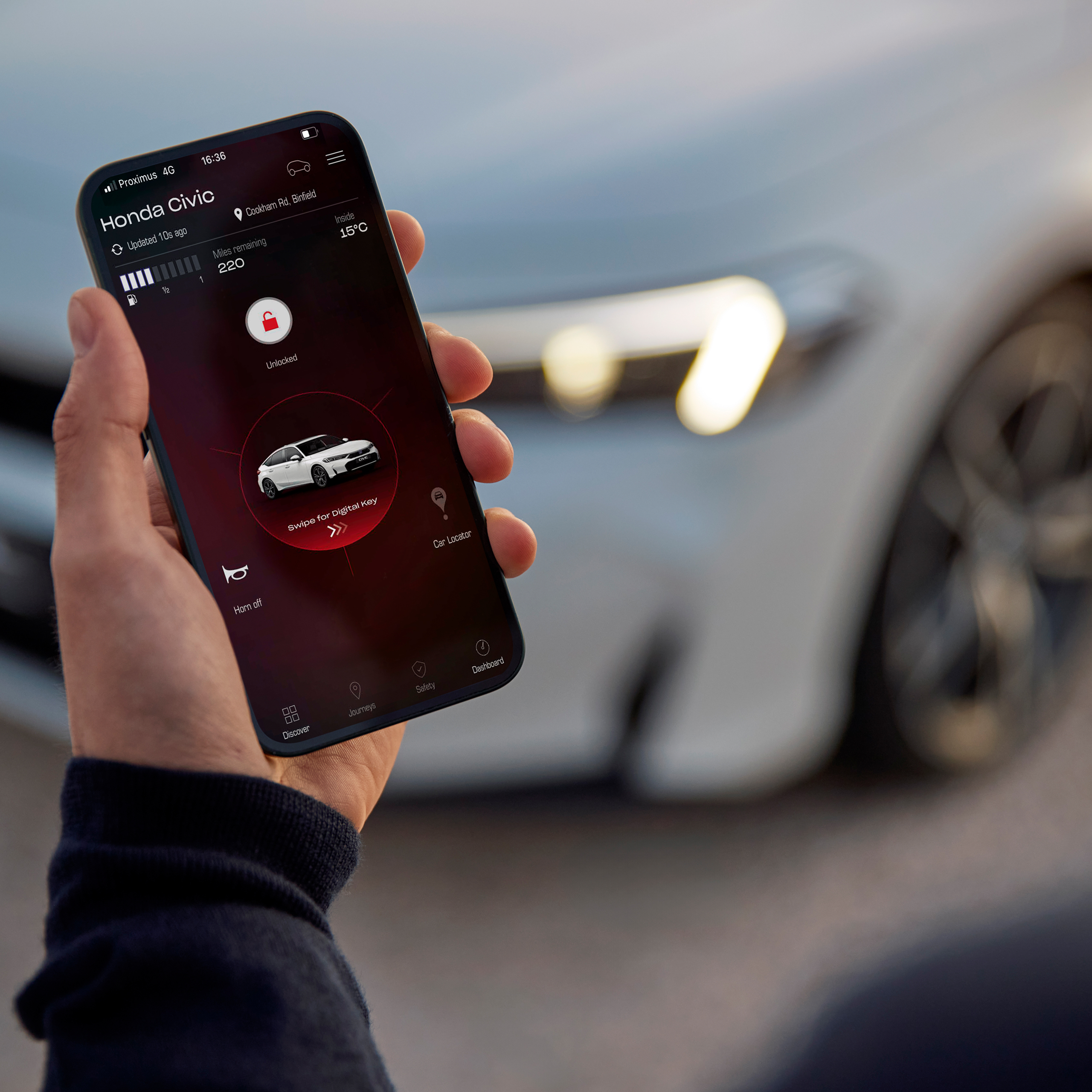 A person holding a smartphone, with My Honda+ app on it.